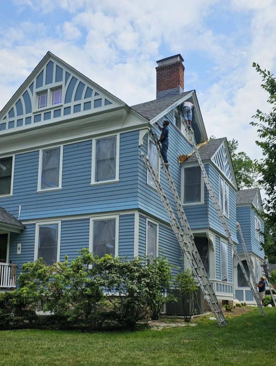 Crew on ladders painting a blue clapboard Fairfield County home with white trim