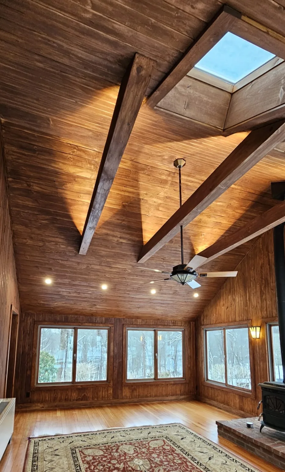 Restored tongue-and-groove wood ceiling, beams and paneling in a sunlit Fairfield County living room